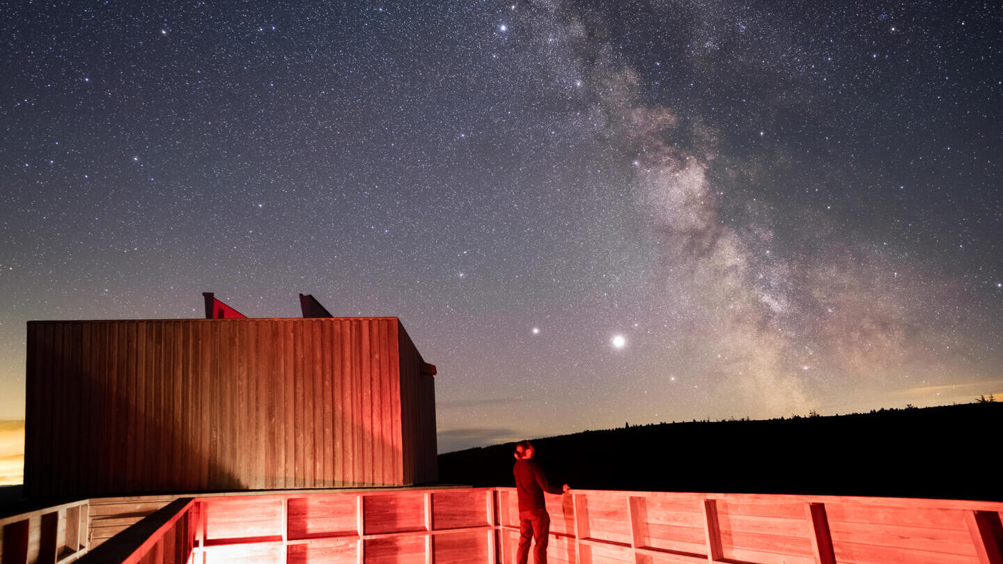 Eine Person beobachtet nachts im Kielder Observatory die Sterne.