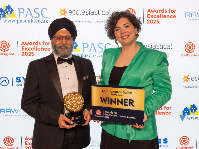 Two winners smiling and posing with their plaque on stage at a gala ceremony.
