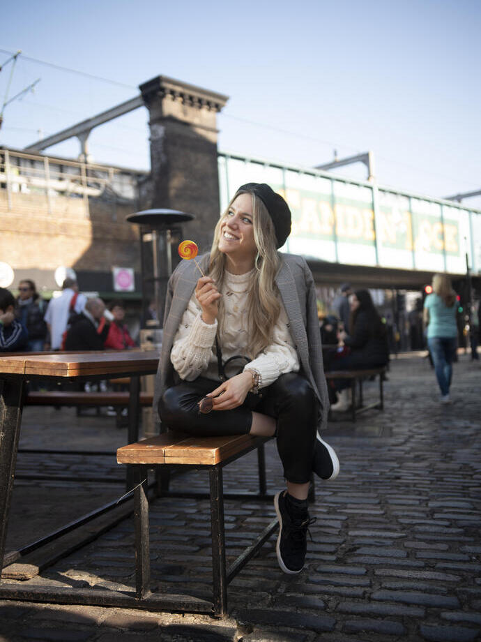 Une femme assise sur un banc, souriante, tenant une sucette