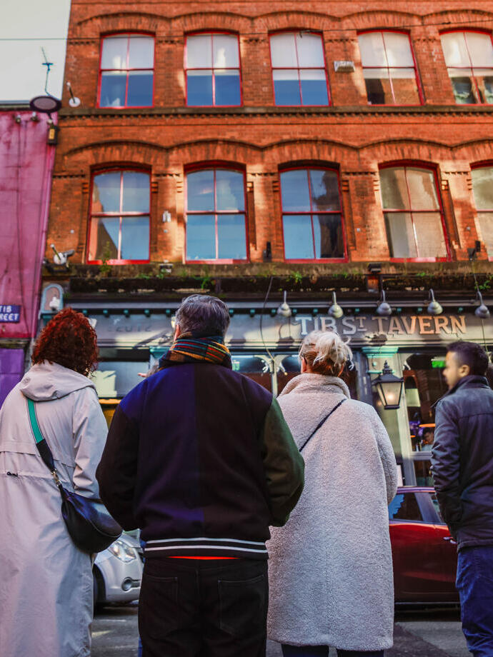 People in a street looking at city buildings on a walking city food tour.