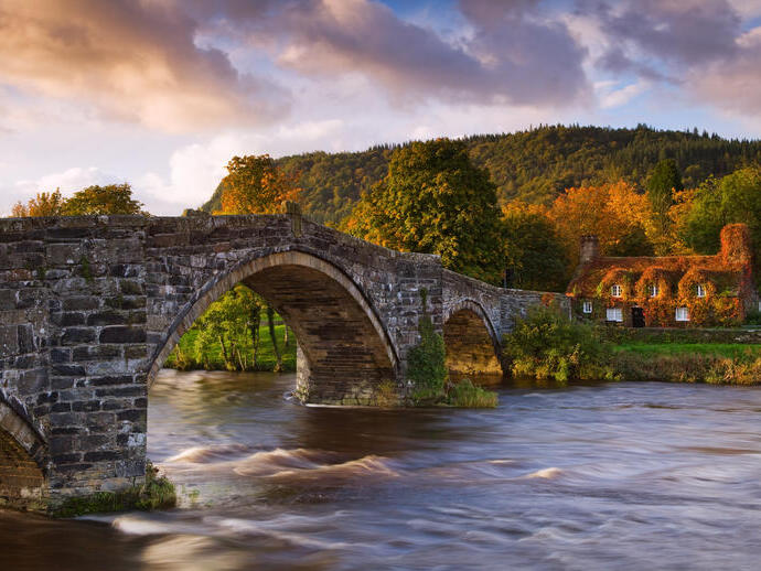 Large stone arched bridge over a flowing river. Sunset