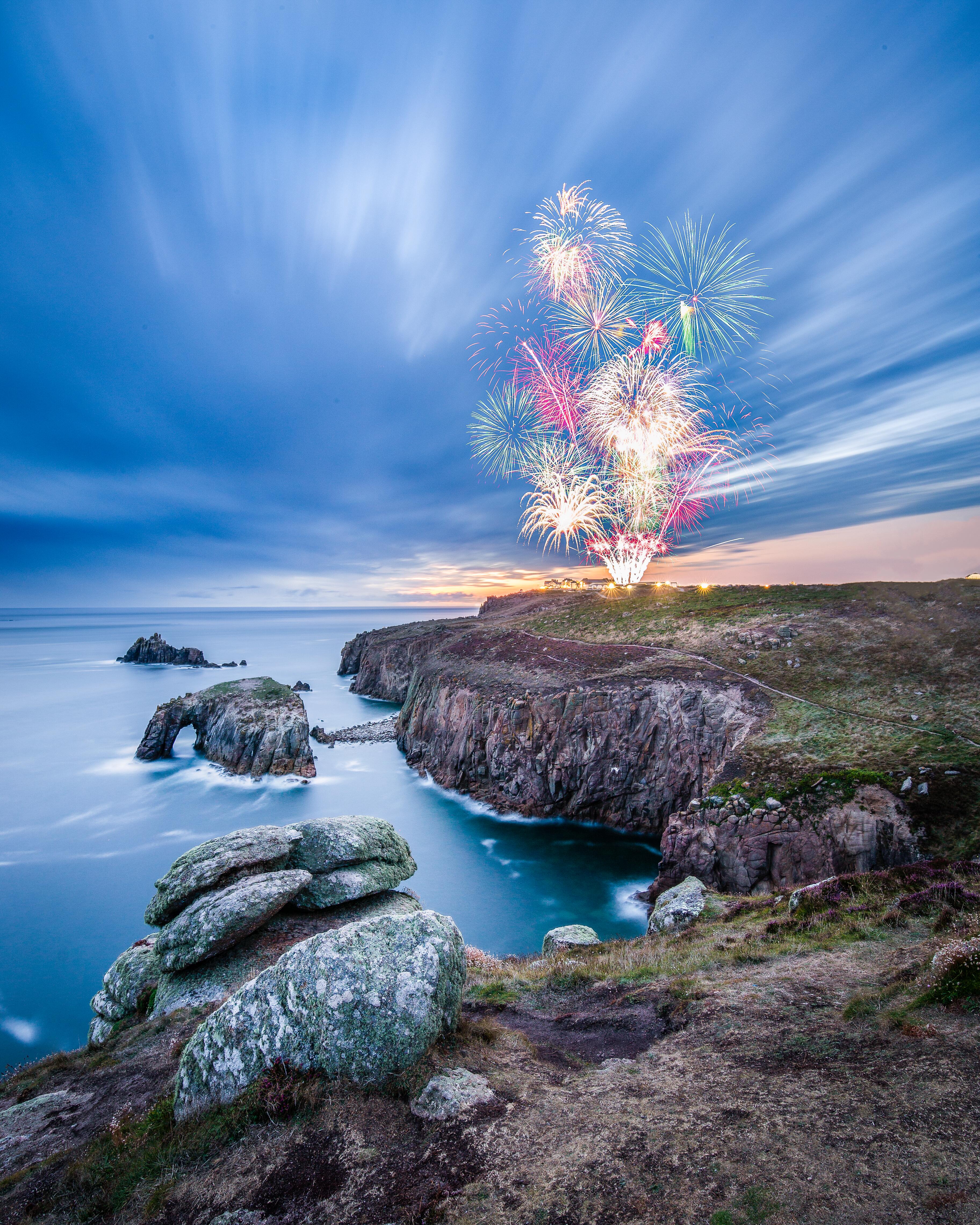 Feu d'artifice vu depuis un promontoire rocheux au crépuscule