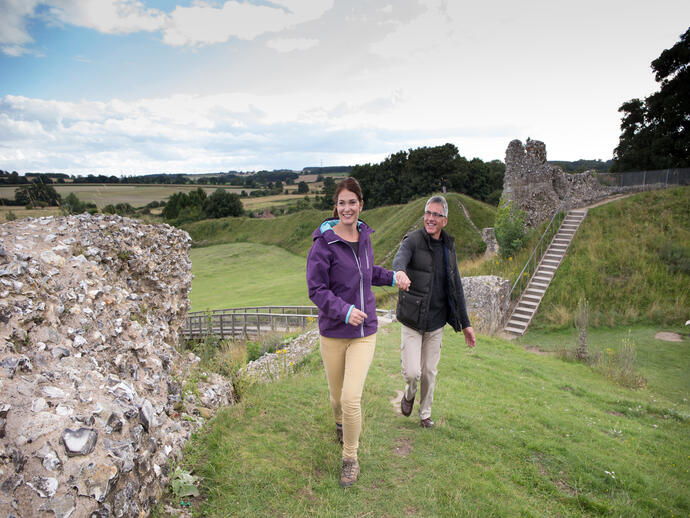 A couple walking along the ruins of Castle Rising West in Norfolk