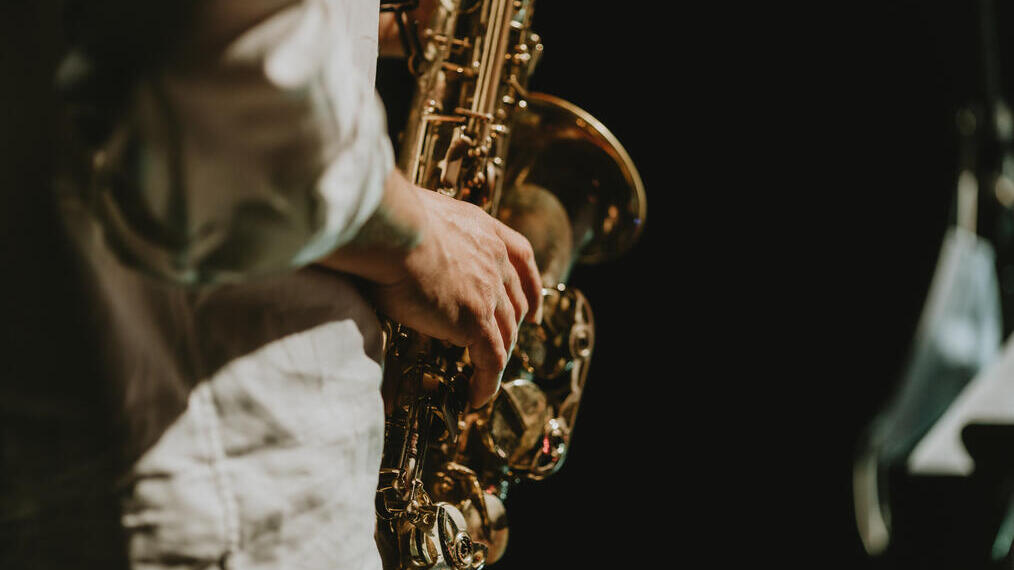 Parte central de un hombre tocando el saxofón en un concierto de música.