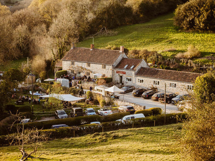 Rural view of a pub from an elevated position looking across fields to the pub in the background.