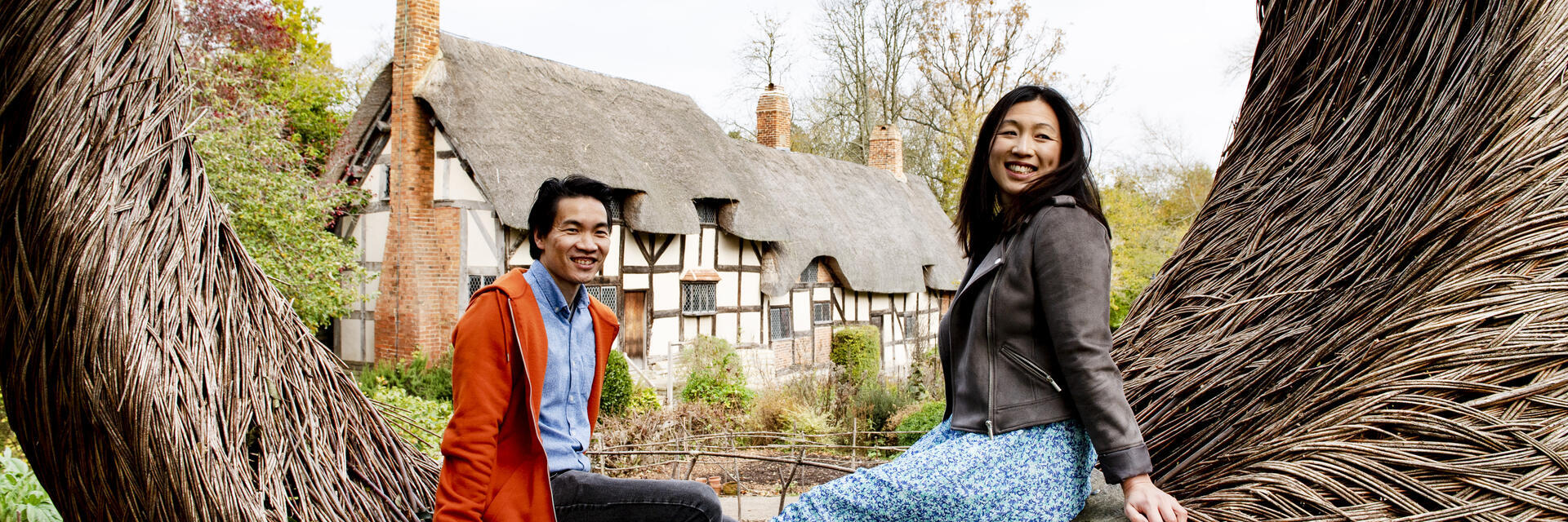 A young couple at Anne Hathaway's Cottage sitting on Tom Hare's 'The Moon Seat', Stratford-upon-Avon, Warwickshire, England