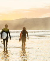 Hombre y mujer, llevando tablas de surf y saliendo del mar