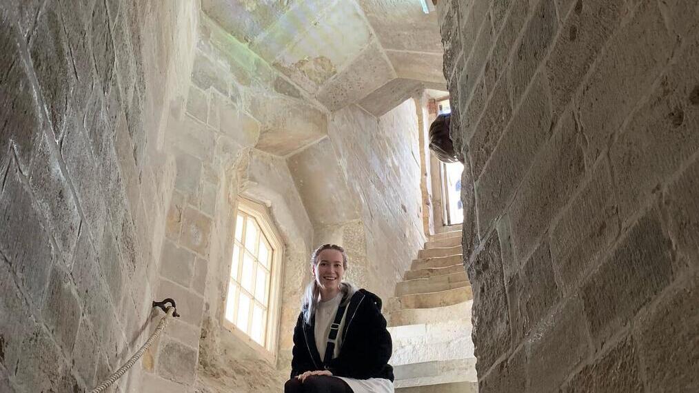 Découvrez l'histoire de manière interactive, femme assise sur un escalier en colimaçon à l'intérieur d'un bâtiment