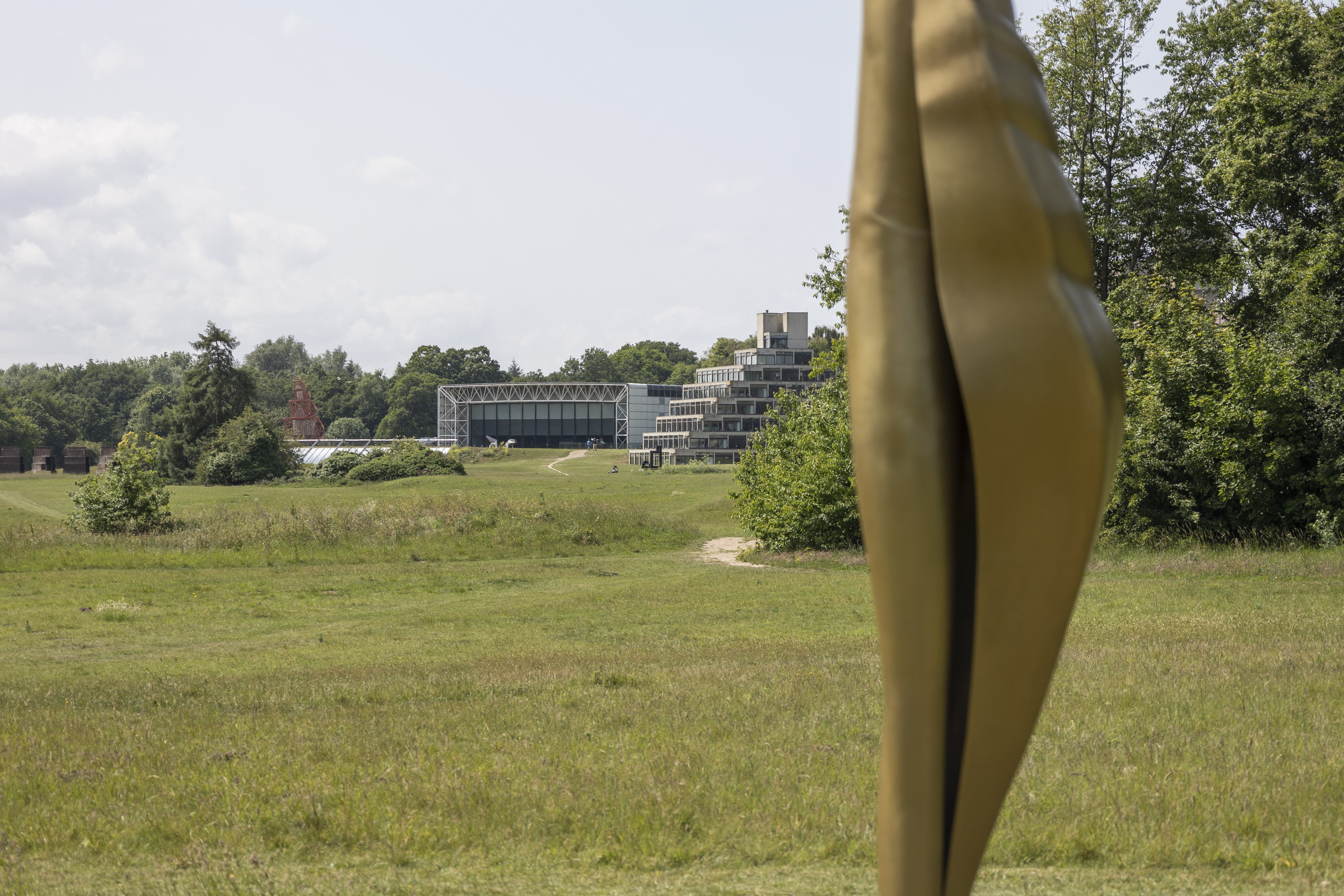 An external shot of a field with a modern building in the background