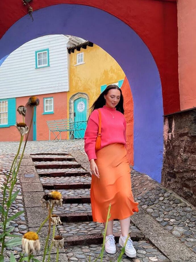 Femme marchant dans une rue pavée, sous une arche colorée