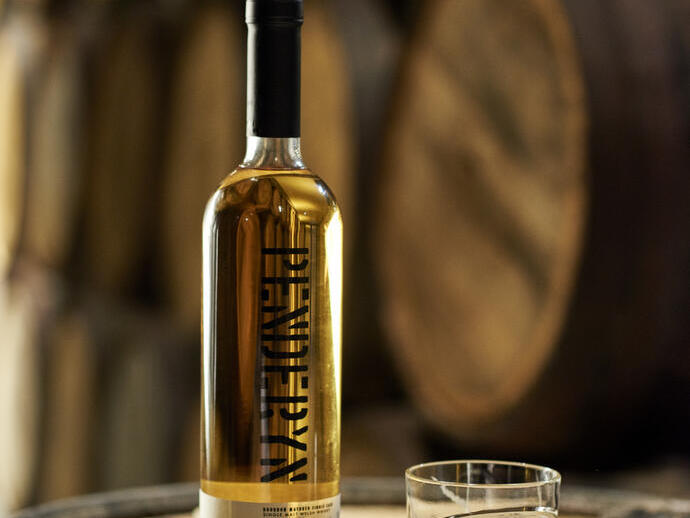 Eine Flasche Whisky und ein Glas Whisky stehen auf einem Eichenfass