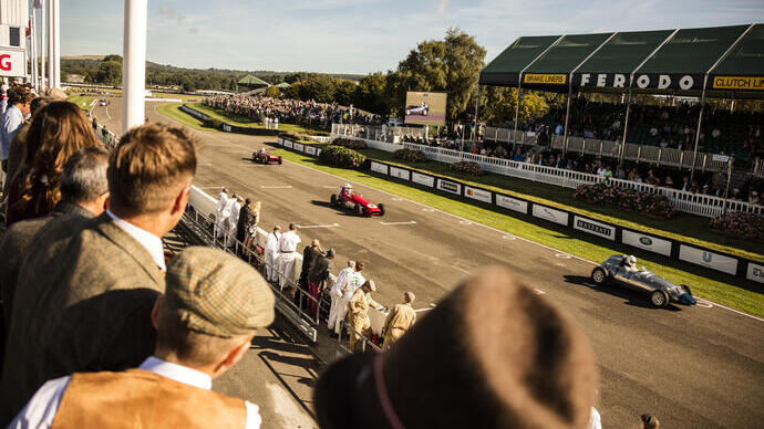 Mensen op een tribune kijken naar een race met oldtimers