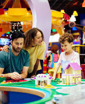 Madre, padre e hijo riendo mientras juegan con Lego