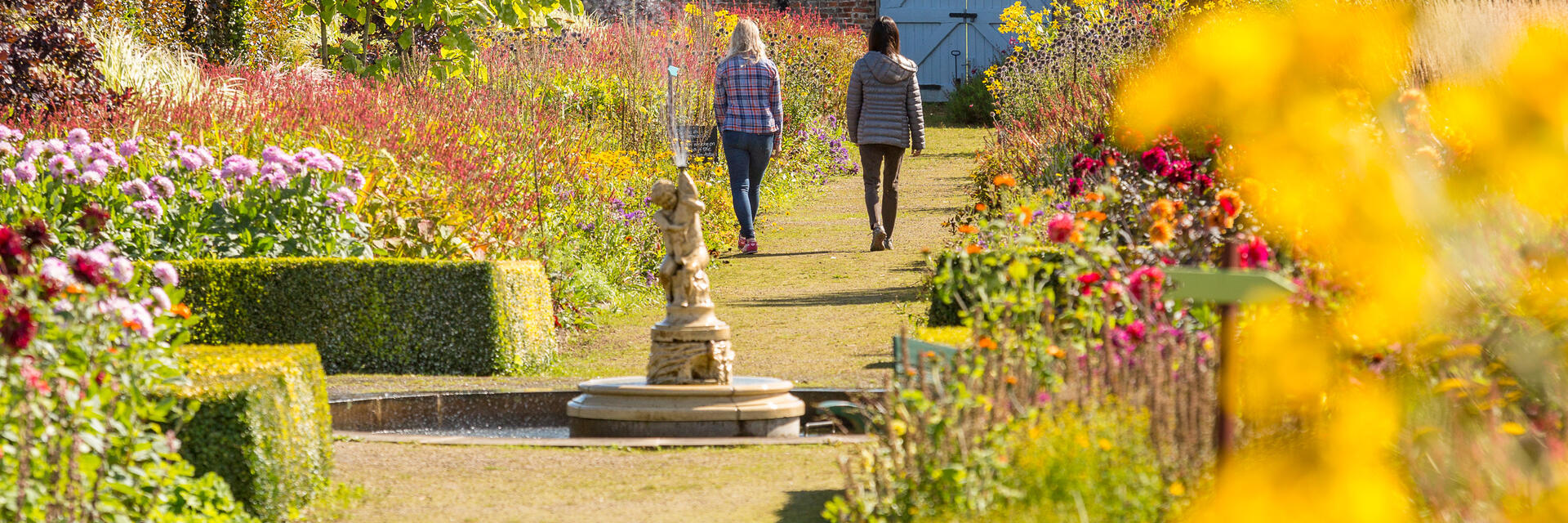 Zwei Freundinnen spazieren durch einen formalen Garten