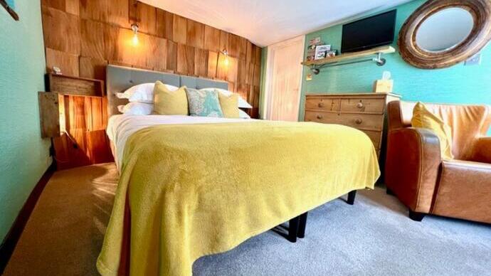 A bedroom with yellow bedspread and a wooden feature wall.