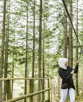 Two women preparing to go on a zipwire in the pine forest