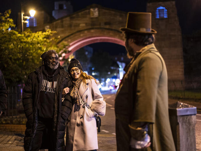 Persone che ascoltano una guida turistica di notte durante una passeggiata fantasma a Chester