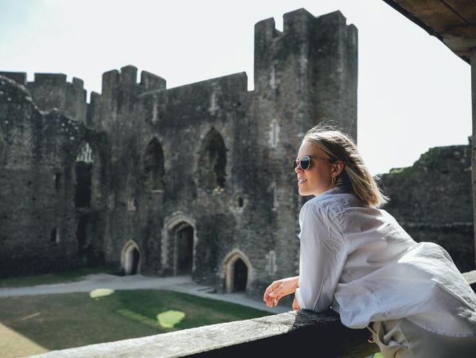 A woman in sunglasses looking out across Caerphilly Castle, Wales