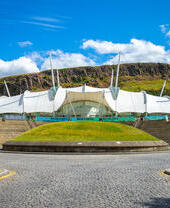 White tent like structure on the side of a cliff with a grass mound in the foreground