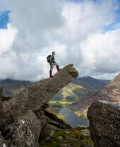 Man standing on a protruding pinnacle rock formation and looking at the view