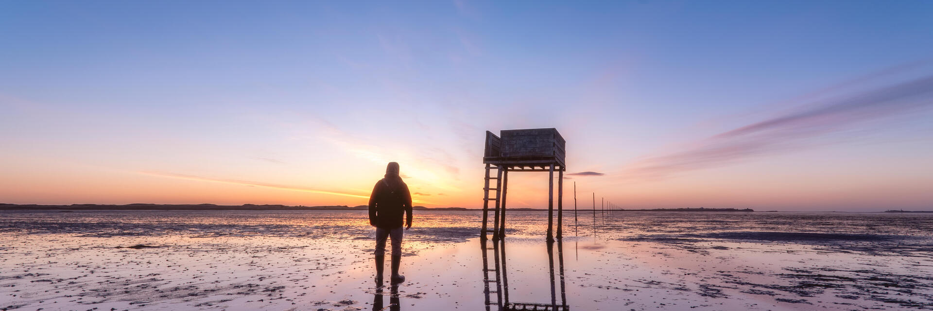 Posts marking the pilgrims' way crossing to Lindisfarne with emergency refuge at sunrise