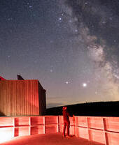 Eine Person beobachtet nachts im Kielder Observatory die Sterne.
