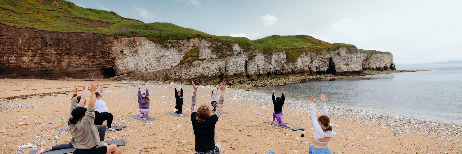 Eine Gruppe von Menschen praktiziert Yoga am Strand