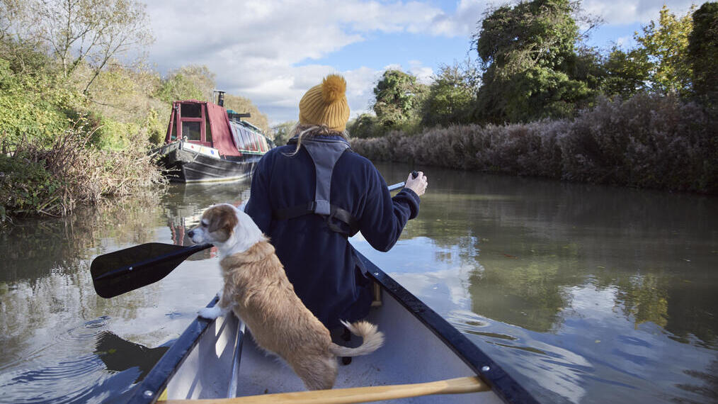 Frau und Hund in einem Ruderboot auf einem Kanal