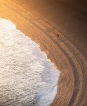 Vista aerea di due persone sulla riva del mare al tramonto
