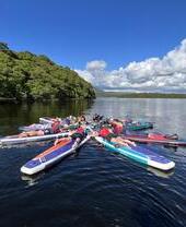 Paddleboarder, die sich auf dem Fluss Clyde in Glasgow hinlegen und eine Form bilden