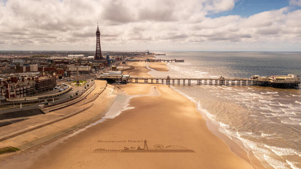 Vista panorámica de una playa de arena con un muelle y una torre.