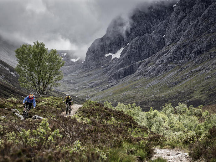 Two mountain bikers cycling on a trail going up a mountain