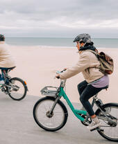 Dos personas en bicicleta frente al paseo marítimo de Bournemouth.