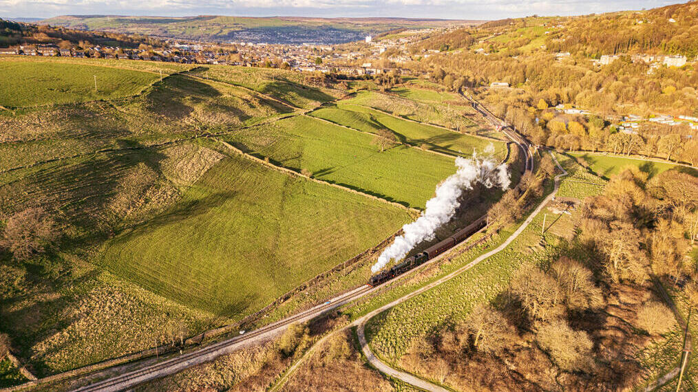 Train à vapeur circulant sur des voies ferrées à la campagne