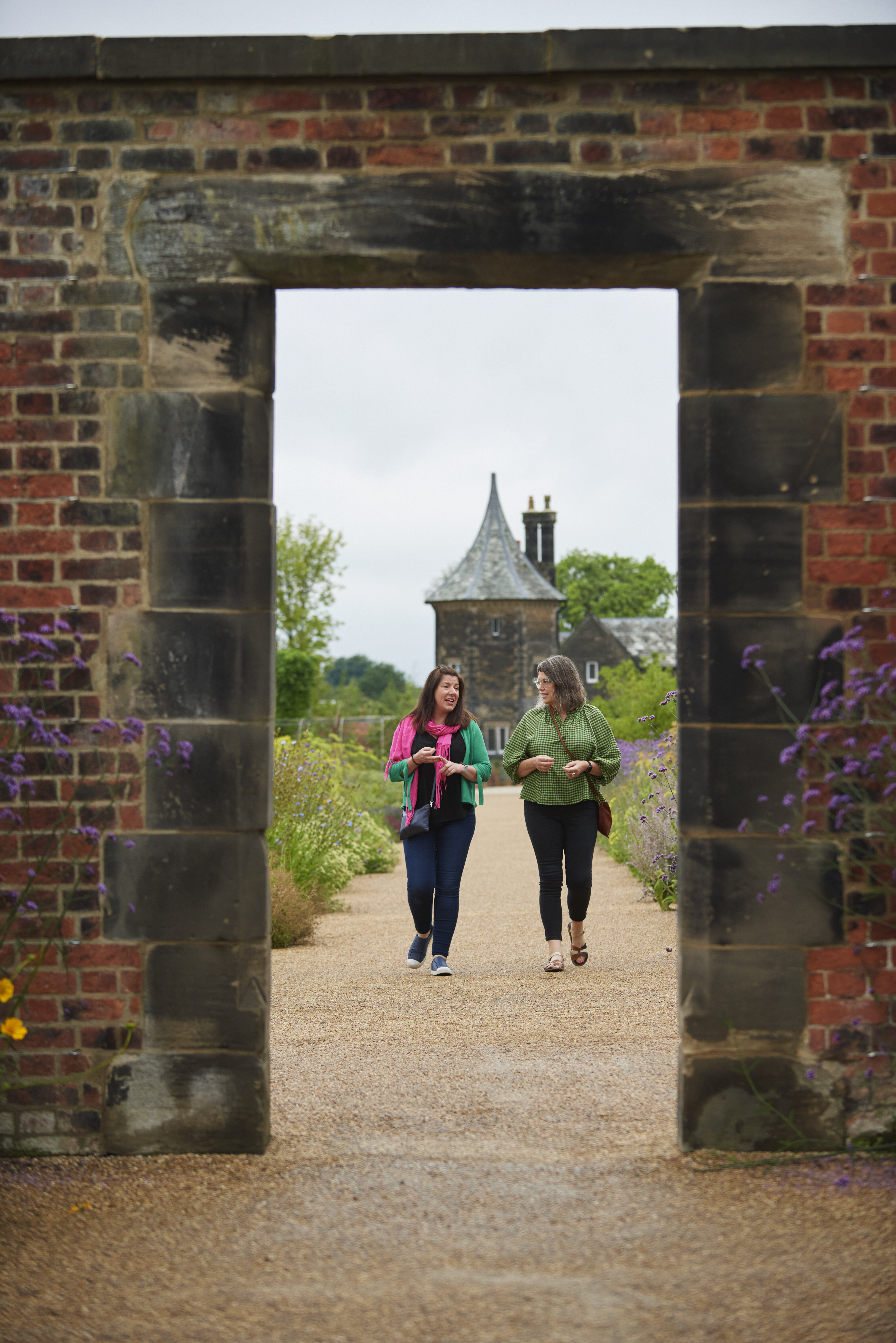 Two women walking toward archway, RHS Bridgewater