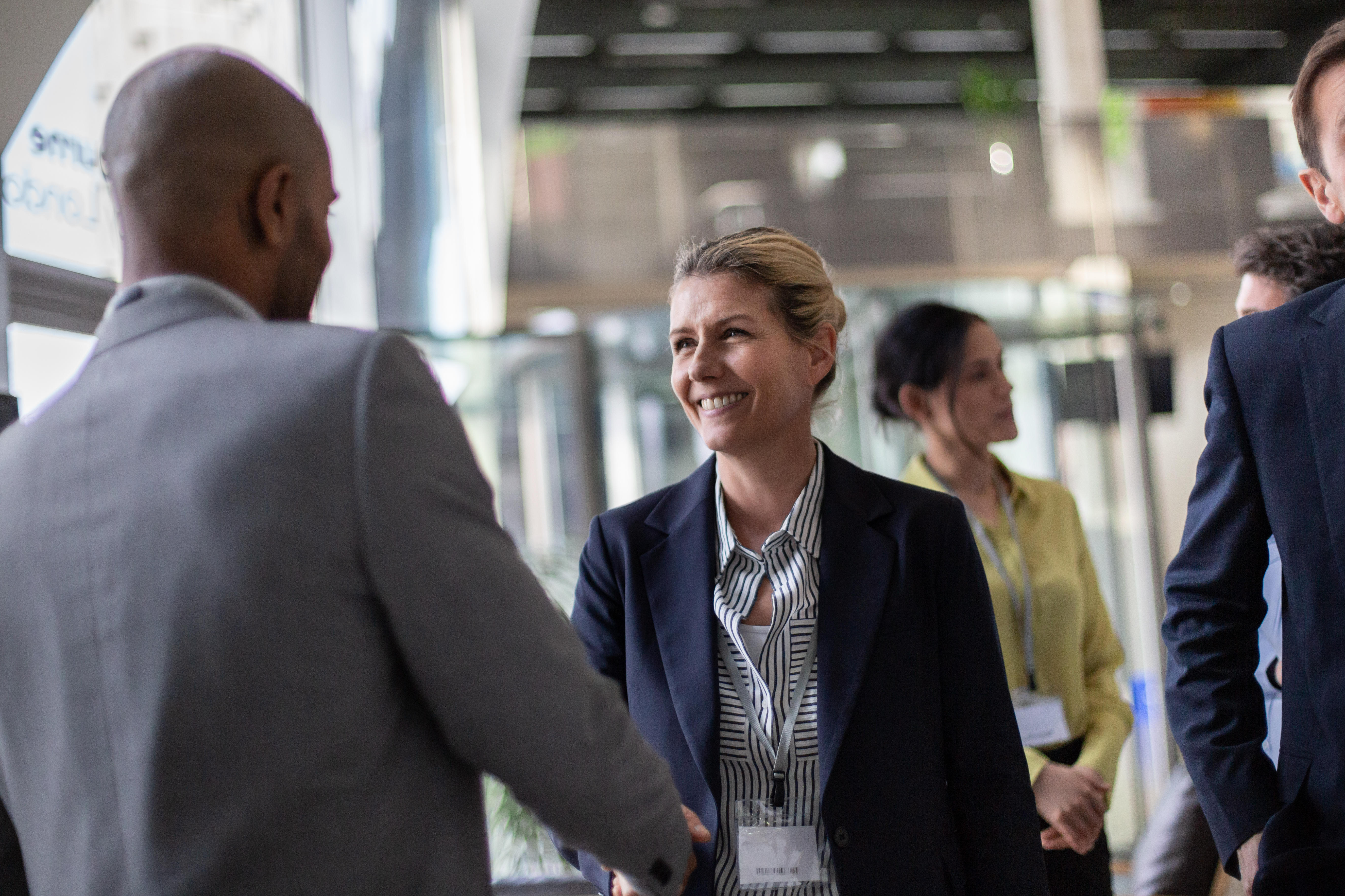 Business professionals interacting and shaking hands in a modern office setting during a networking event.