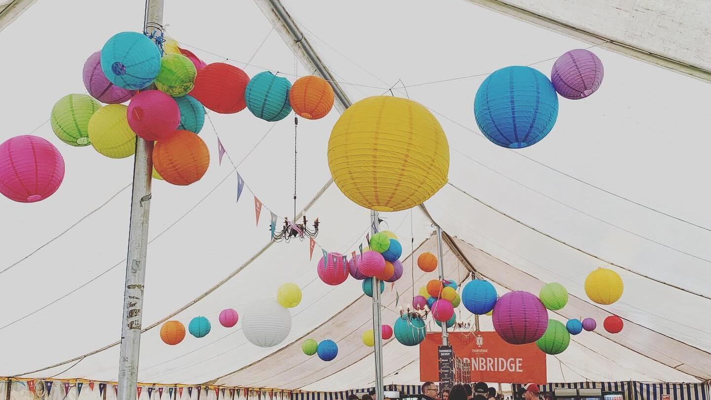 Summer-party time, people in a large tent with colourful lanterns