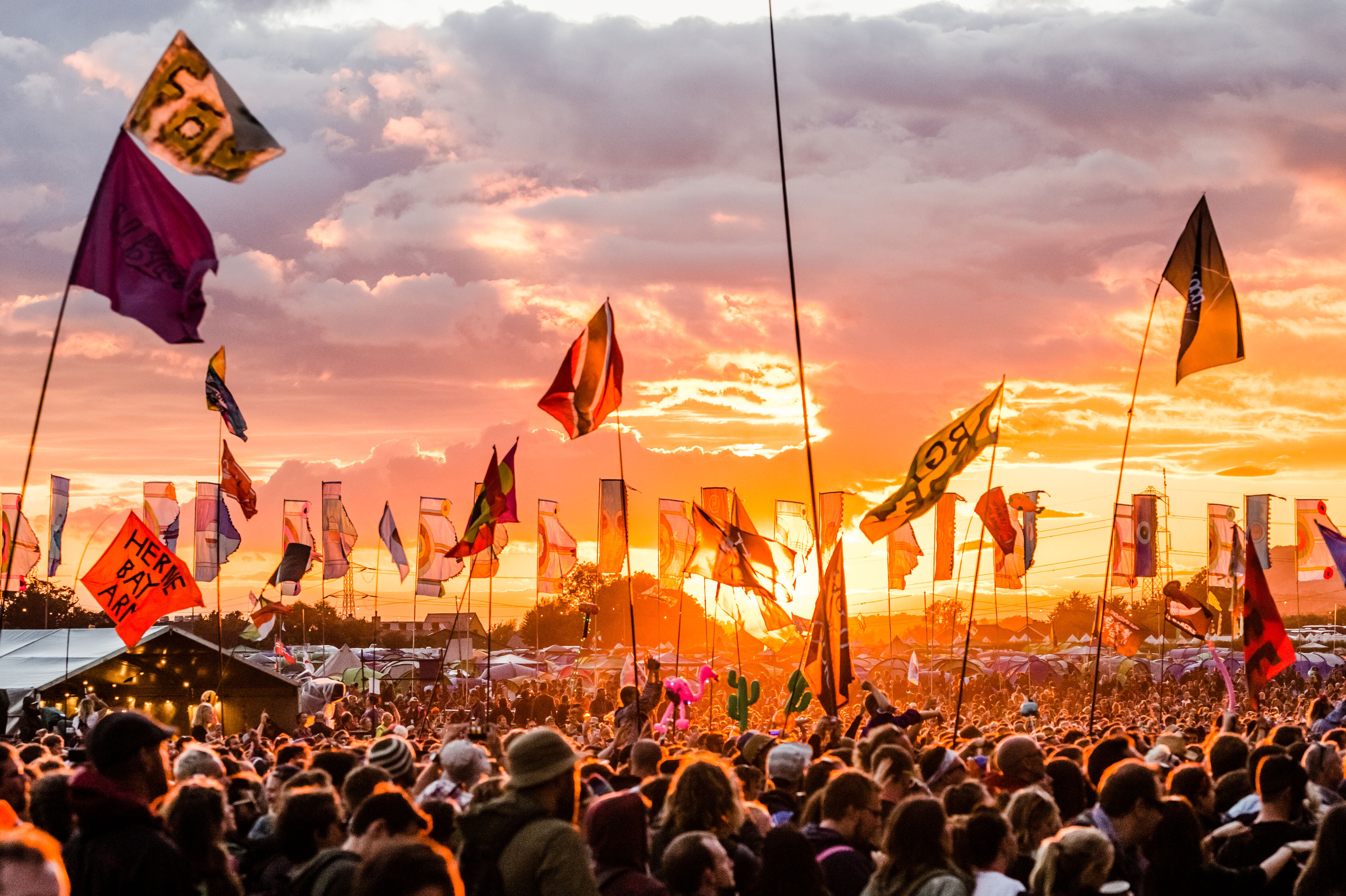 Festival de Glastonbury, montrant une foule de personnes au coucher du soleil, agitant des drapeaux