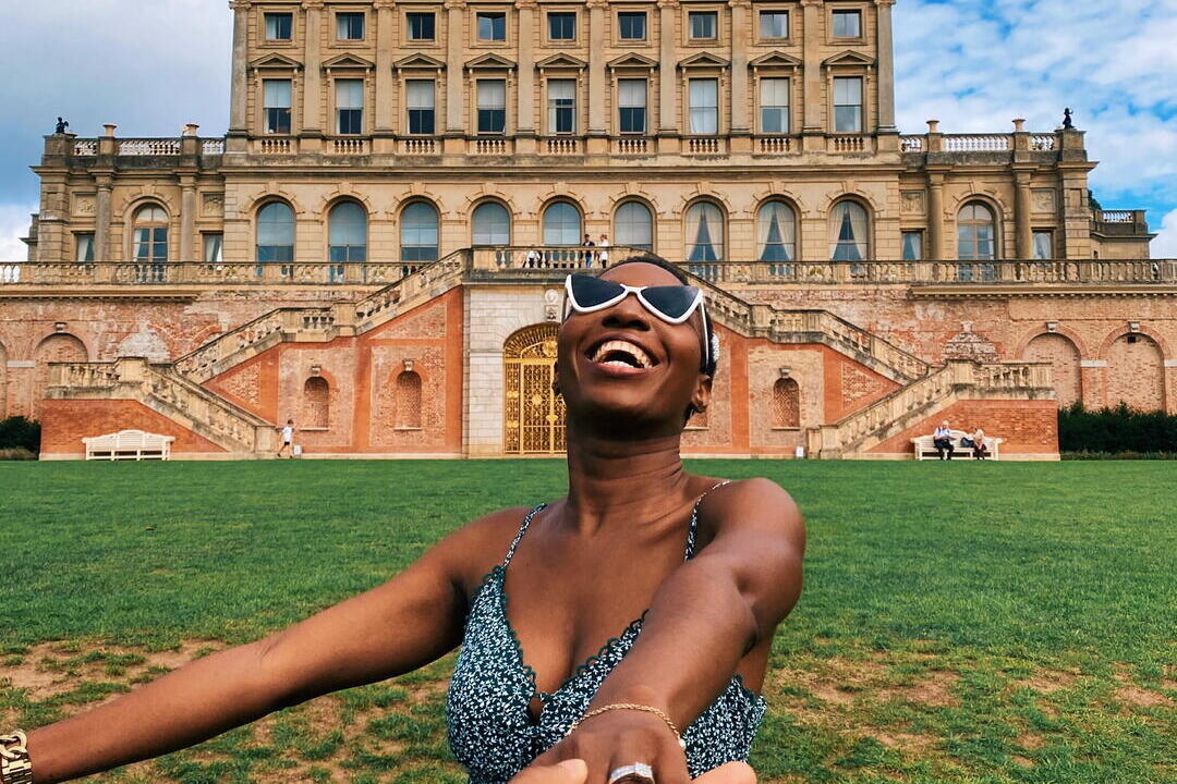 Smiling woman, wearing sunglasses and sundress, outside Cliveden Hotel