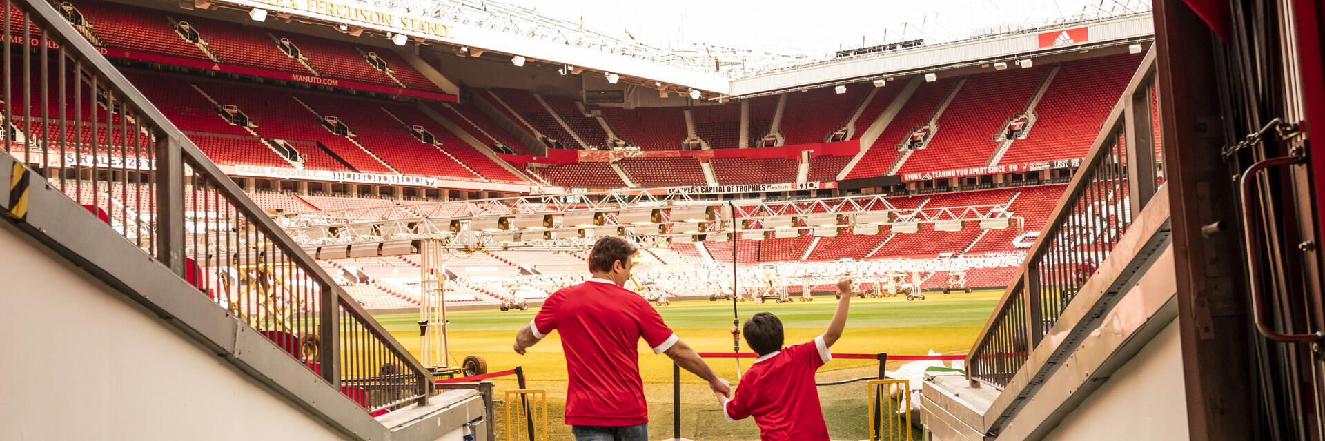 Un hombre y un niño en el túnel del estadio mirando hacia el campo