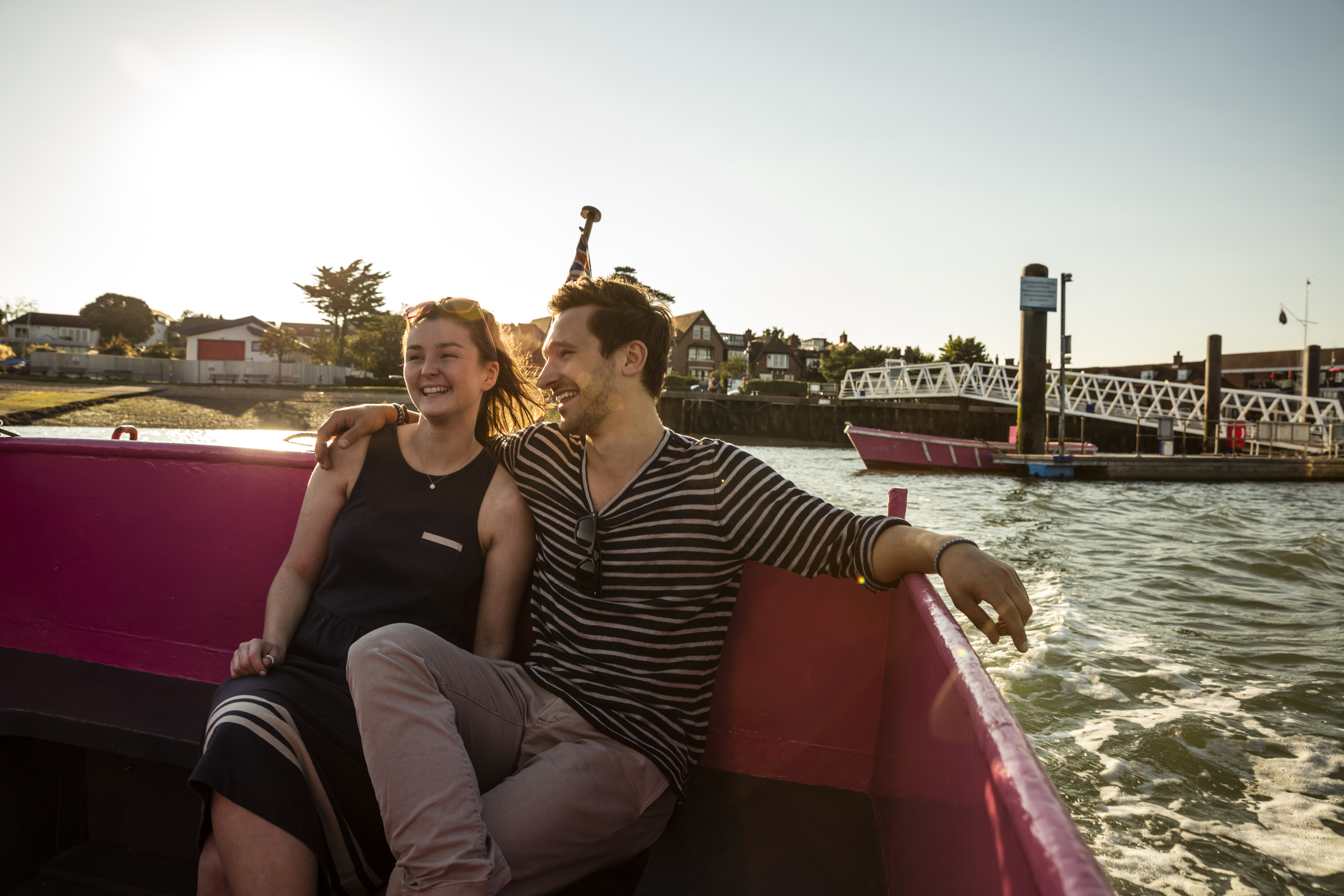 A couple seated on a bench on deck in evening sunshine