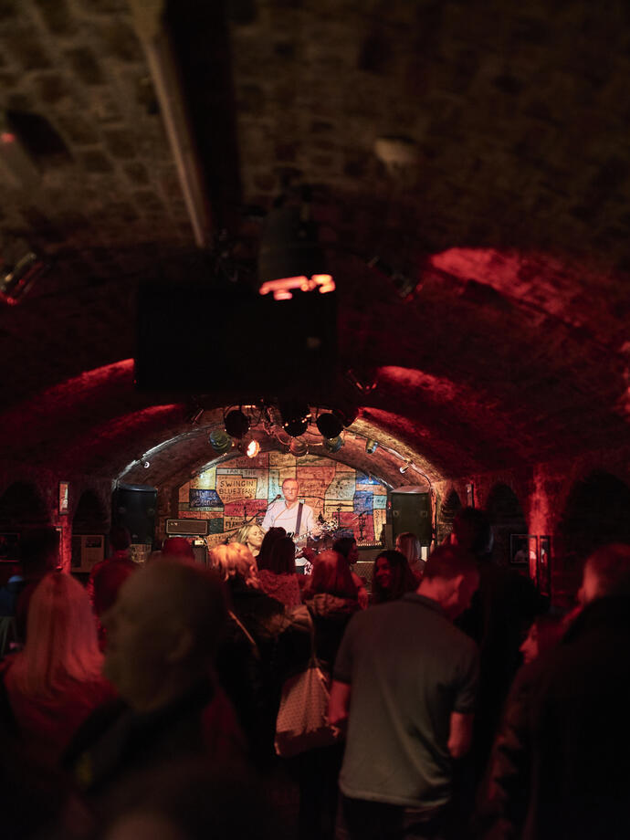 Brick tunnel-shaped room with music act on stage.