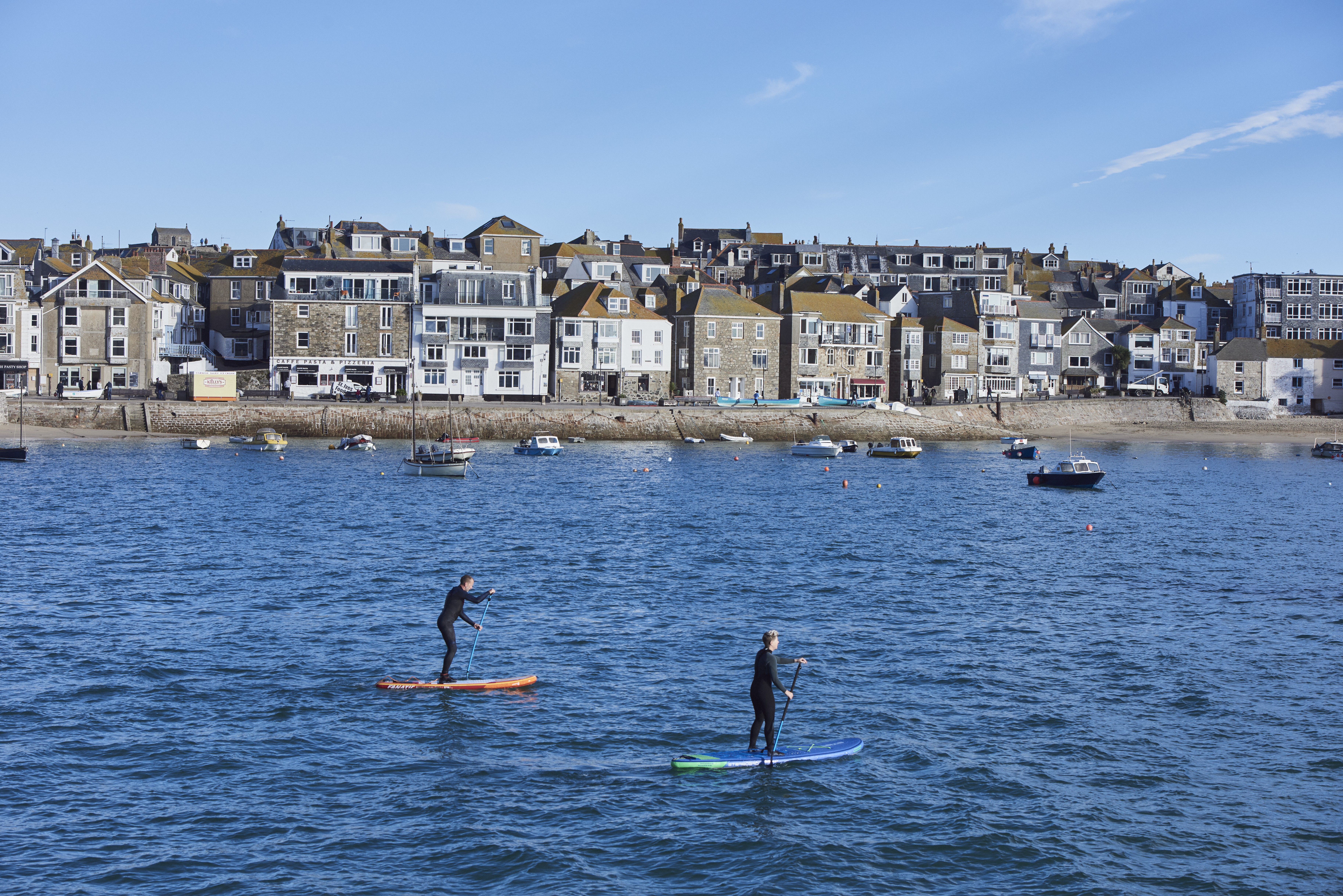 Two people on paddle boards floating in a harbour