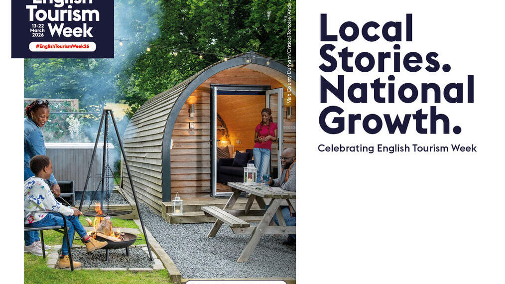People enjoy a campfire and picnic outside a wooden cabin surrounded by trees, promoting English Tourism Week in County Durham, North East.