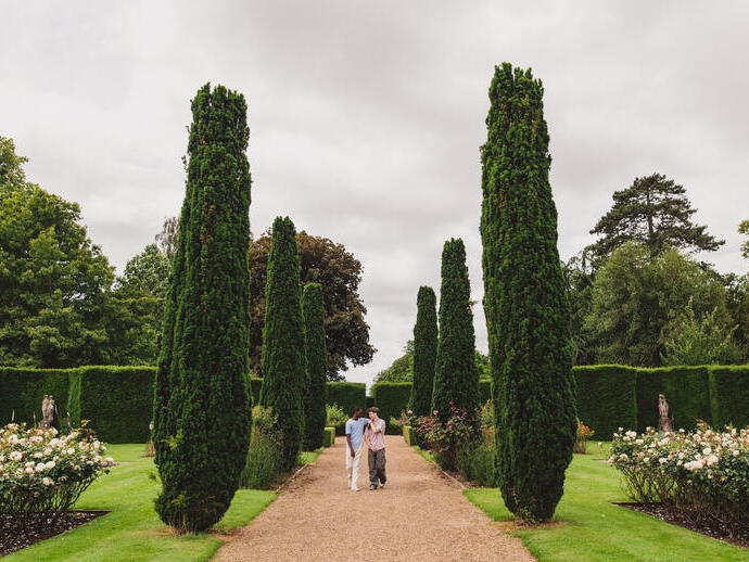 Two young men walk through ornate gardens