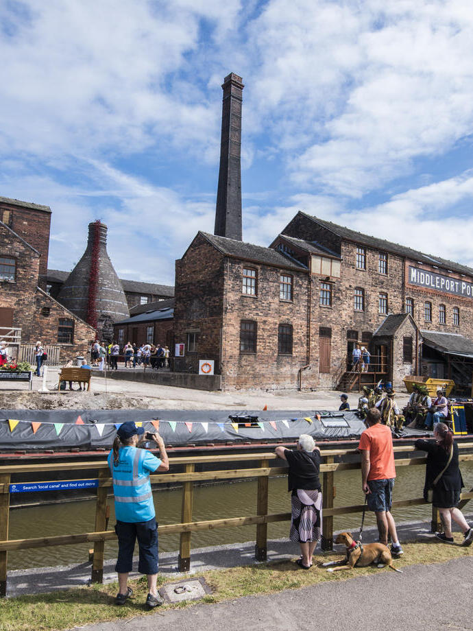 A group of people looking across the Trent and Mersey Canal at several historic buildings in Stoke