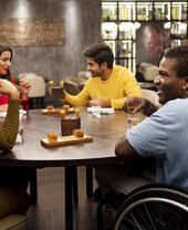 Group of friends, one in a wheelchair sitting at a table in a restaurant