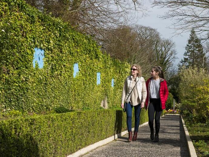Deux femmes marchant le long d'une haie dans un parc