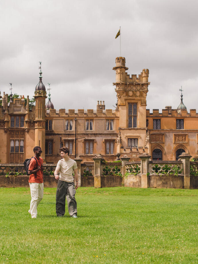 Two young men walk in the grounds of a heritage house