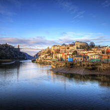 A city on the banks of a river with a large bridge in the distance